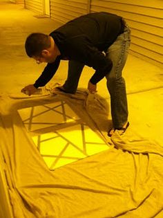 a man standing on top of a yellow tarp in the middle of a driveway