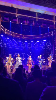 a group of people standing on top of a stage in front of a blue light