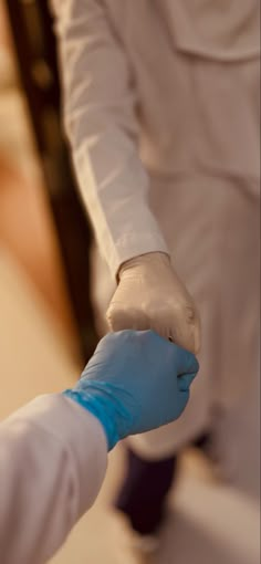 two people in white suits and blue gloves holding hands