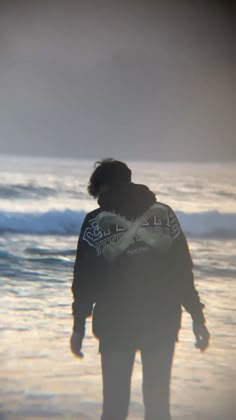 a man standing on top of a beach next to the ocean