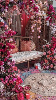 a room filled with lots of pink flowers next to a white couch and wooden table