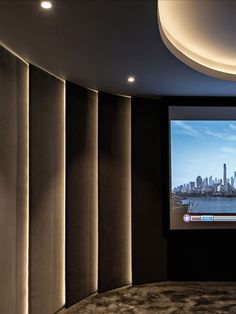 an empty room with a large screen on the wall and city skyline in the background