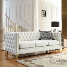 a white couch sitting on top of a hard wood floor next to a stair case