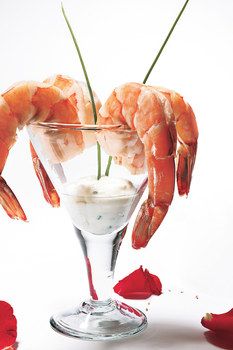 the shrimp is garnished with white sauce and served in a martini glass for two