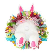 a white stuffed animal laying on top of a wreath with pink and green decorations around it