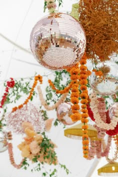 a disco ball hanging from the ceiling in front of flowers and other decorations on display