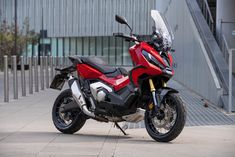 a red and black motorcycle parked in front of a building