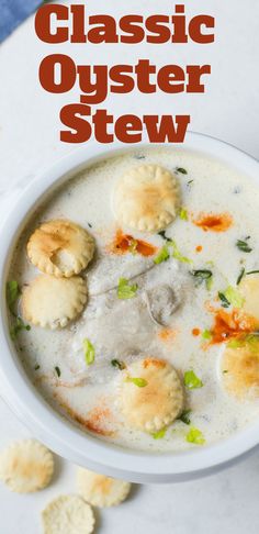 a white bowl filled with soup and dumplings next to crackers on the side