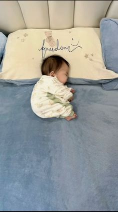 a baby laying on top of a blue bed