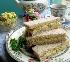 three sandwiches stacked on top of each other on a plate next to a cup of coffee