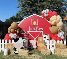 there are many farm animals in front of the barn and hay bales on the ground