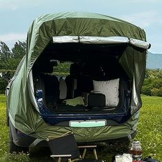 the back end of an suv with its trunk open and camping gear on the ground