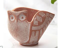 an owl shaped clay bowl sitting on top of a white table next to a potted plant