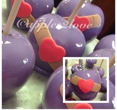 there are purple apples with hearts on them and sticks sticking out of the top one