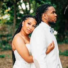 a bride and groom standing together in the woods