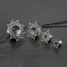 three pieces of silver jewelry sitting on top of a black stone surface with one piece missing