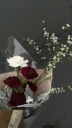 a bouquet of roses is wrapped in tin foil and placed on the water's edge