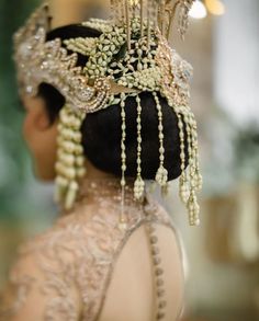 the back of a woman's head with pearls and beads on it, wearing a tiara