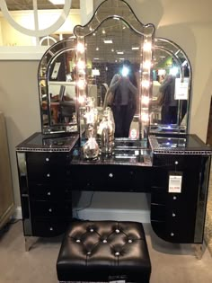 a black vanity with lights on it and a foot stool