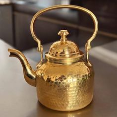 a gold tea kettle sitting on top of a table