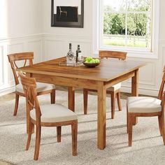 a dining room table with four chairs and a bowl of fruit on the counter top