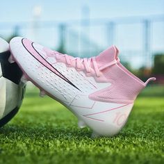 a soccer ball sitting next to a white and pink shoe on top of a green field