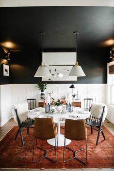 a dining room with black walls and white trim on the ceiling is decorated in modern style