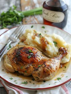 a white plate topped with chicken and mashed potatoes next to a bottle of wine