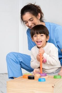 a woman playing with a child on the floor in front of a wooden toy box