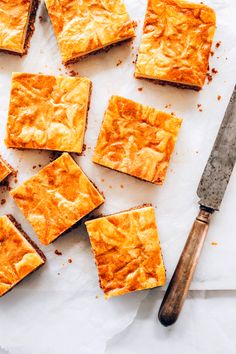 several squares of food sitting on top of a piece of paper next to a knife