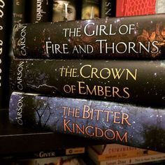 three books stacked on top of each other in front of a book shelf filled with books