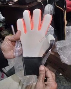 a man holding up a white and orange glove with neon lights on it's fingers