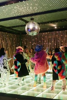 several people dressed in brightly colored clothing and disco balls