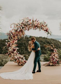 a bride and groom standing under an arch with flowers