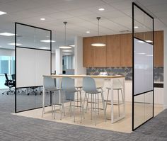 an empty office with chairs and desks in the middle of the room is seen through glass partitions