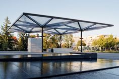 an empty pavilion sits in the middle of a city street with trees and buildings behind it