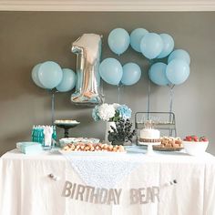 a table topped with blue balloons and cake