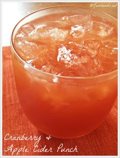 a glass filled with ice sitting on top of a wooden table next to a red cloth