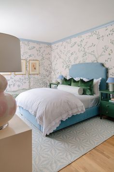 a bedroom with blue and white wallpaper, green headboard, and bed