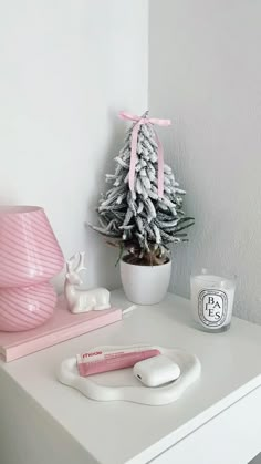 a white desk with a pink christmas tree and other items on it next to a candle