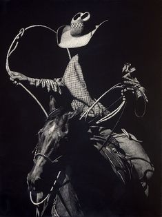 a man riding on the back of a horse wearing a hat and holding a lasso