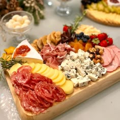 an assortment of cheeses and meats on a wooden platter