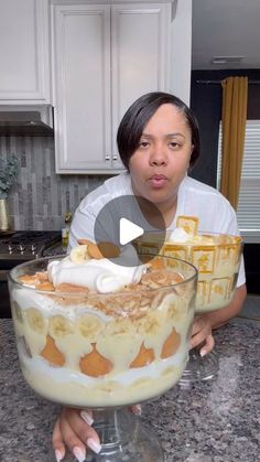 a woman holding a large glass bowl filled with food and ice cream on top of a kitchen counter