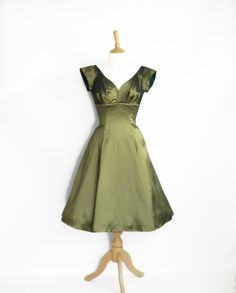 "This elegant 1940s inspired evening dress is made from a rich olive green shot taffeta in our sweetheart bodice with cap sleeves on a knee length panel skirt Like all our dresses it is fully lined, has no stretch and opens with a zip at the back. This dress is ready made and available off-the-peg in a size UK 18 (US 16/EU 46). It has been made to fit a waist measurement of 35.5-36.5\" (89-93cm) and a bust measurement of 43-44\" (108-112cm). It will fit a hip/bottom measurement of 45-47\" (114-1 Elegant Green Dresses, Prom Dress Aesthetic, Dresses 70s, Dig For Victory, Dress Shorts Outfit, Green Shot, Short Green Dress, Elegant Casual Dress, Dama Dresses