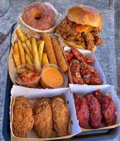 a tray filled with different types of food next to french fries and donuts on top of each other