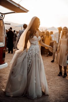 a woman in a wedding dress standing next to a van