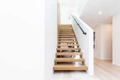 there is a wooden stair case in the house with white walls and wood flooring