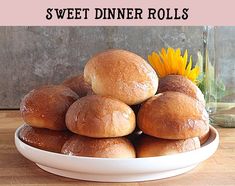 a white bowl filled with rolls on top of a wooden table next to a sunflower