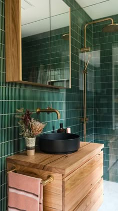 a bathroom with green tiled walls and wooden vanity