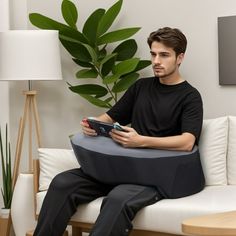 a man sitting on top of a white couch holding a remote control in his hand